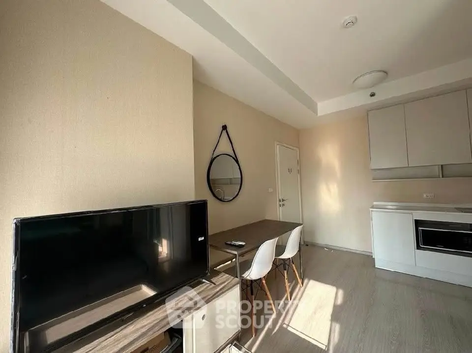 Modern living room with TV, dining area, and compact kitchen in a cozy apartment.
