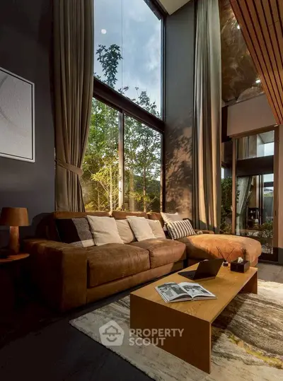 Luxurious living room with high ceilings and large windows offering garden views.