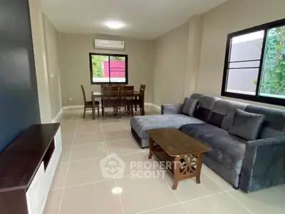 Spacious living room with modern furniture and dining area, featuring large windows and sleek tile flooring.