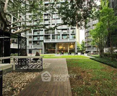 Modern apartment building with lush garden and outdoor seating area.