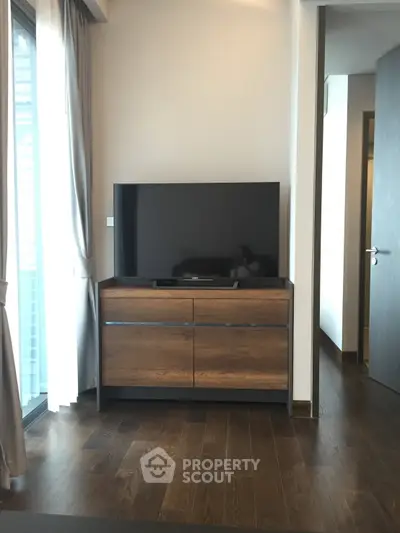 Modern living room with sleek TV stand and large flat-screen TV, featuring elegant wooden flooring and natural light.