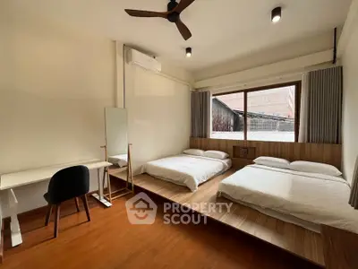 Spacious bedroom with two beds, wooden flooring, and a study area, perfect for comfort and productivity.