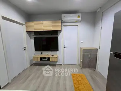 Modern living room with sleek design, featuring wall-mounted TV, air conditioning, and stylish storage solutions.