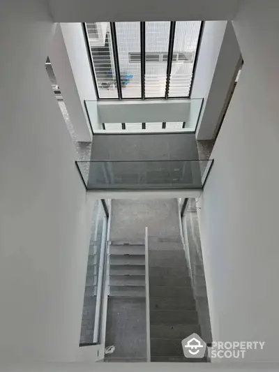 Modern staircase with glass railing and large windows in contemporary building