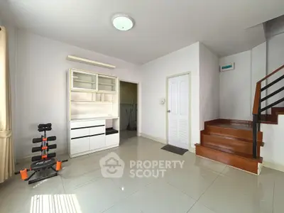 Spacious living room with modern decor and exercise equipment, featuring sleek staircase and ample natural light.