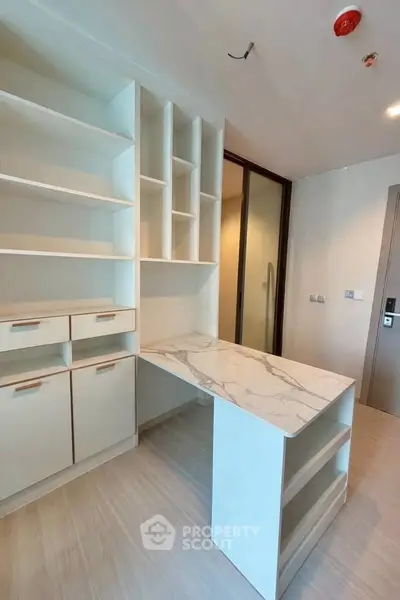 Modern study room with built-in shelves and marble desk in a sleek apartment.