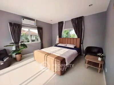 Spacious bedroom with modern decor and large windows offering natural light