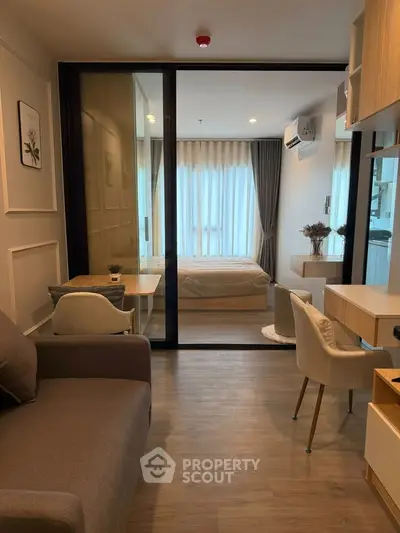 Modern studio apartment with glass partition, cozy living area, and stylish decor.