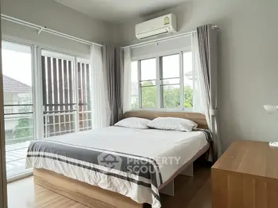 Bright and airy bedroom with large windows and modern furnishings, perfect for relaxation and comfort.