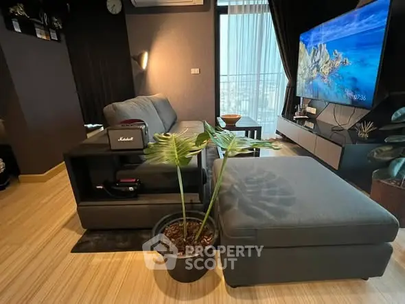 Modern living room with stylish furniture and large TV, featuring a cozy ambiance.