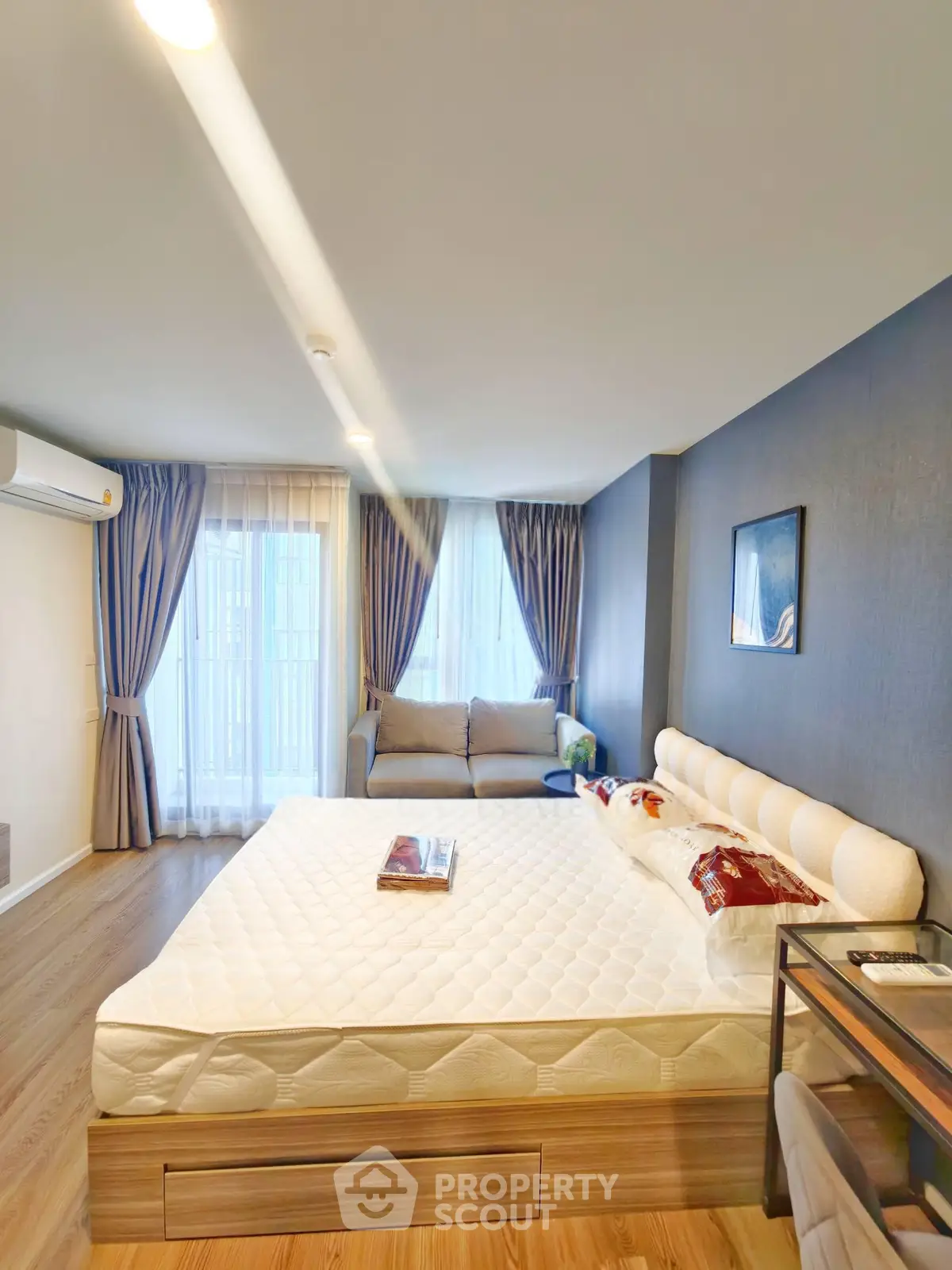 Modern bedroom with stylish decor, large windows, and cozy seating area.