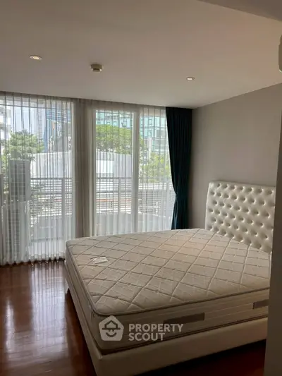 Spacious bedroom with large windows and elegant decor in modern apartment.