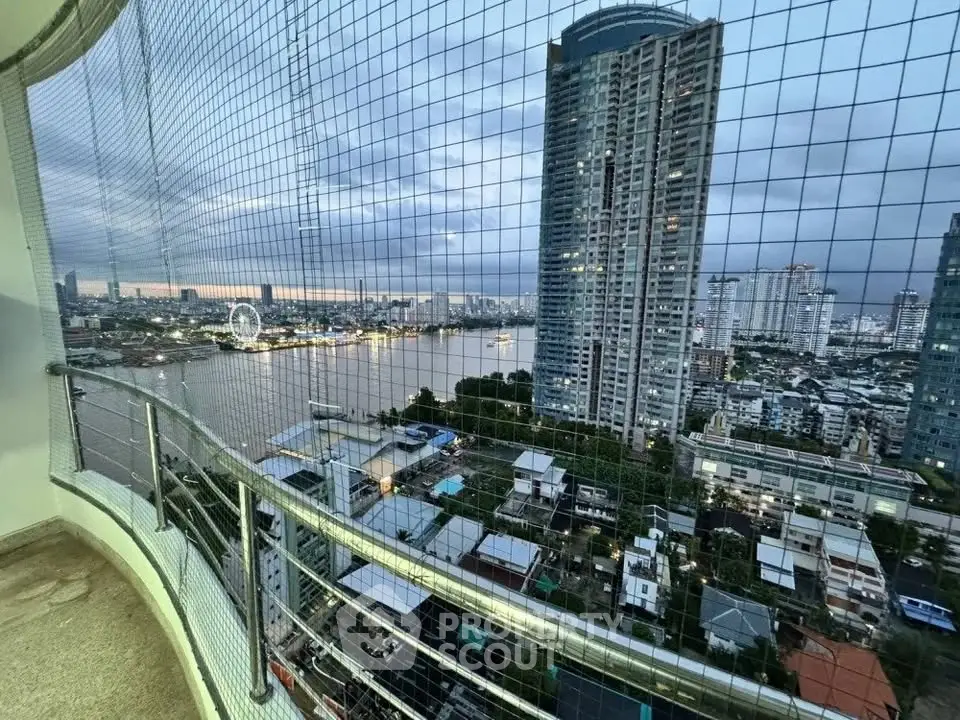 Stunning high-rise balcony view overlooking river and cityscape at dusk, perfect for urban living.