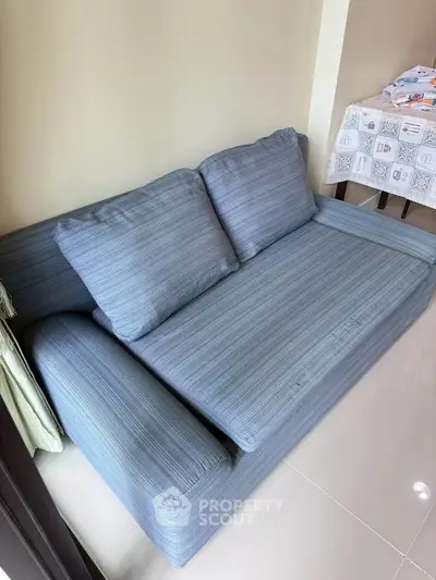 Cozy blue sofa in a modern living room with glossy tiled flooring, perfect for relaxation.
