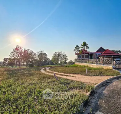 Charming countryside property with expansive green fields and a picturesque house under a clear blue sky.