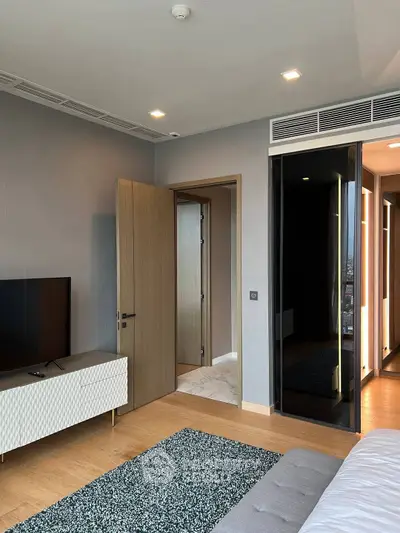 Modern living room with sleek design and large TV, featuring a stylish rug and mirrored wardrobe.