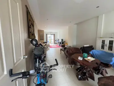 Spacious living room with unique wooden furniture and bike storage, leading to a bright balcony.
