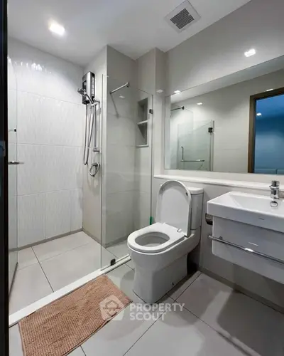 Modern bathroom with glass shower and sleek fixtures in contemporary apartment.