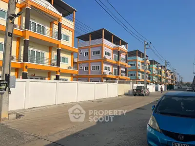 Colorful modern apartment buildings with balconies on a sunny street, showcasing urban living.