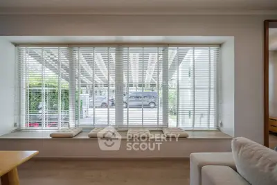 Spacious living room with large window and cozy seating area, perfect for relaxation and natural light.