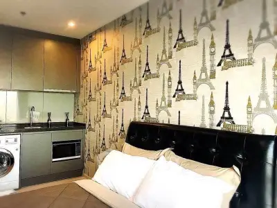 Chic studio apartment with stylish Paris-themed wallpaper and modern kitchenette.