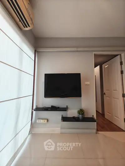 Modern living room with wall-mounted TV and sleek decor in a stylish apartment.
