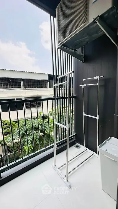 Modern balcony with laundry rack and air conditioning unit, offering a view of neighboring buildings.