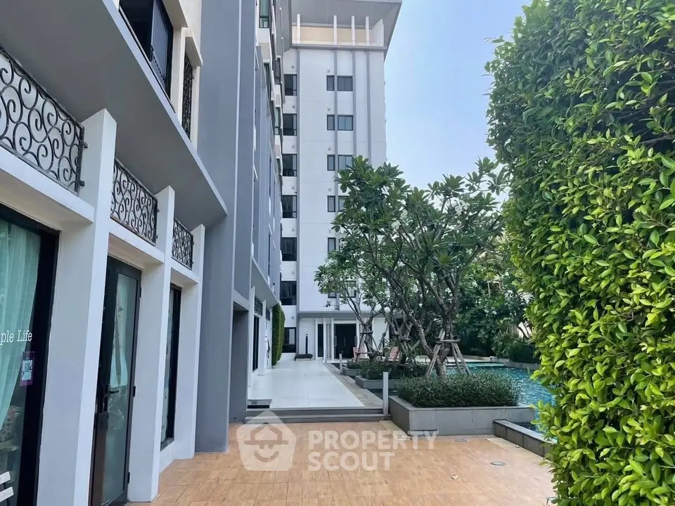Modern apartment building with pool and lush greenery, offering a serene urban living experience.