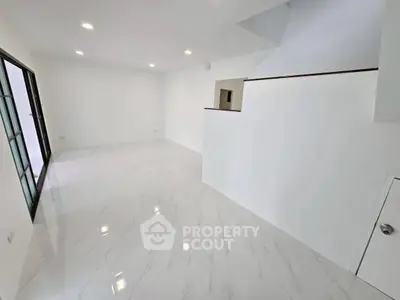 Spacious modern living room with sleek white flooring and ample natural light.