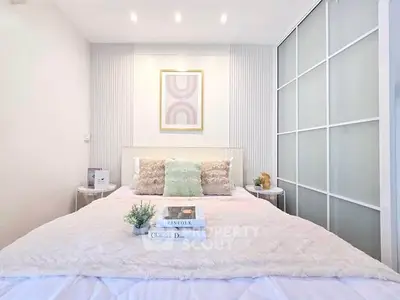 Modern bedroom with stylish decor and sliding closet doors, featuring cozy bedding and elegant wall art.
