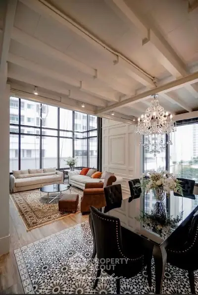 Luxurious living room with elegant chandelier and large windows offering city views.
