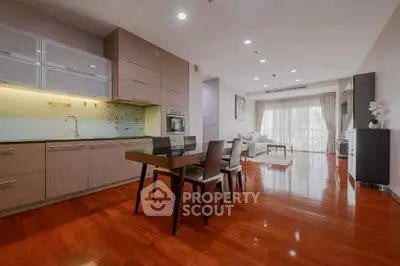 Spacious open-plan living room with modern kitchen and elegant dining area, featuring polished wooden floors and ample natural light.