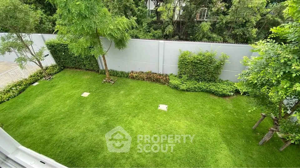 Lush green garden with manicured lawn and trees, perfect for outdoor relaxation and leisure.