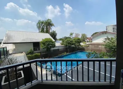 Charming residential view with pool and lush greenery under a clear blue sky.