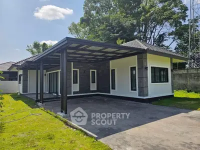 Modern single-story house with spacious driveway and lush green surroundings.