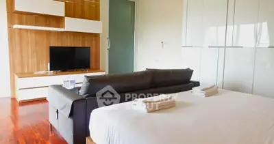 Modern bedroom with sleek design, featuring a cozy bed, stylish sofa, and flat-screen TV for ultimate relaxation.