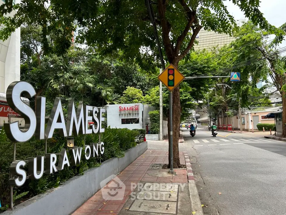 Siamese Surawong entrance with lush greenery and street view