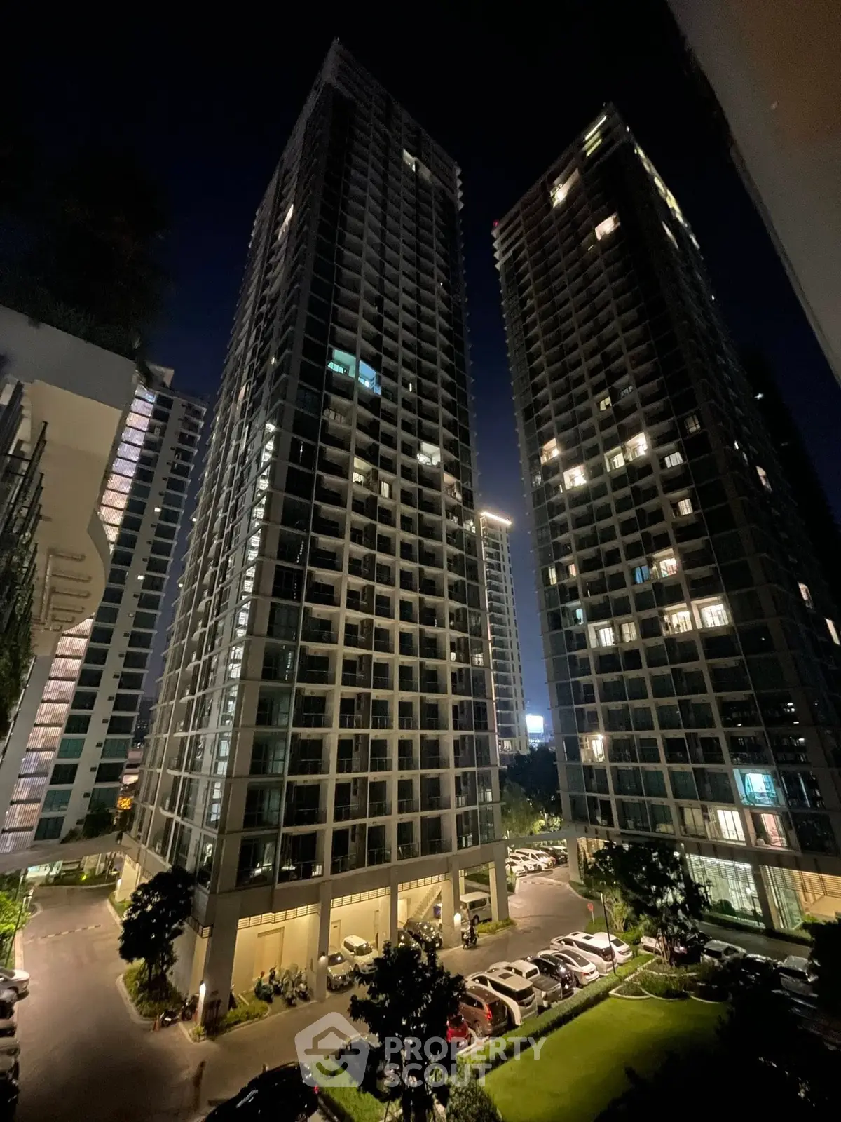 Stunning night view of modern high-rise residential towers with illuminated windows and landscaped surroundings.