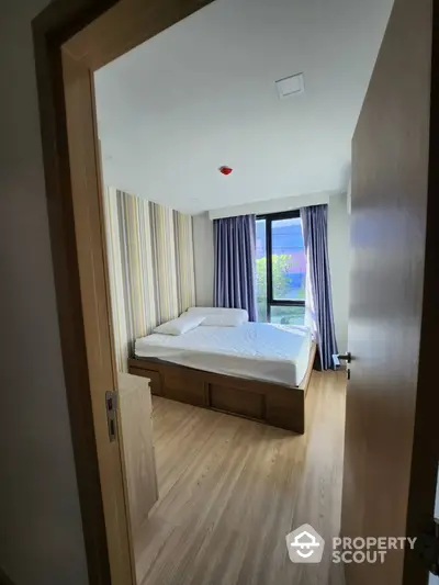 Modern bedroom with large window and stylish decor in a contemporary apartment.