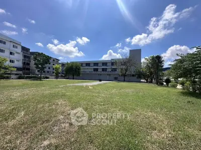 Spacious green lawn with a view of a modern building under a clear blue sky.