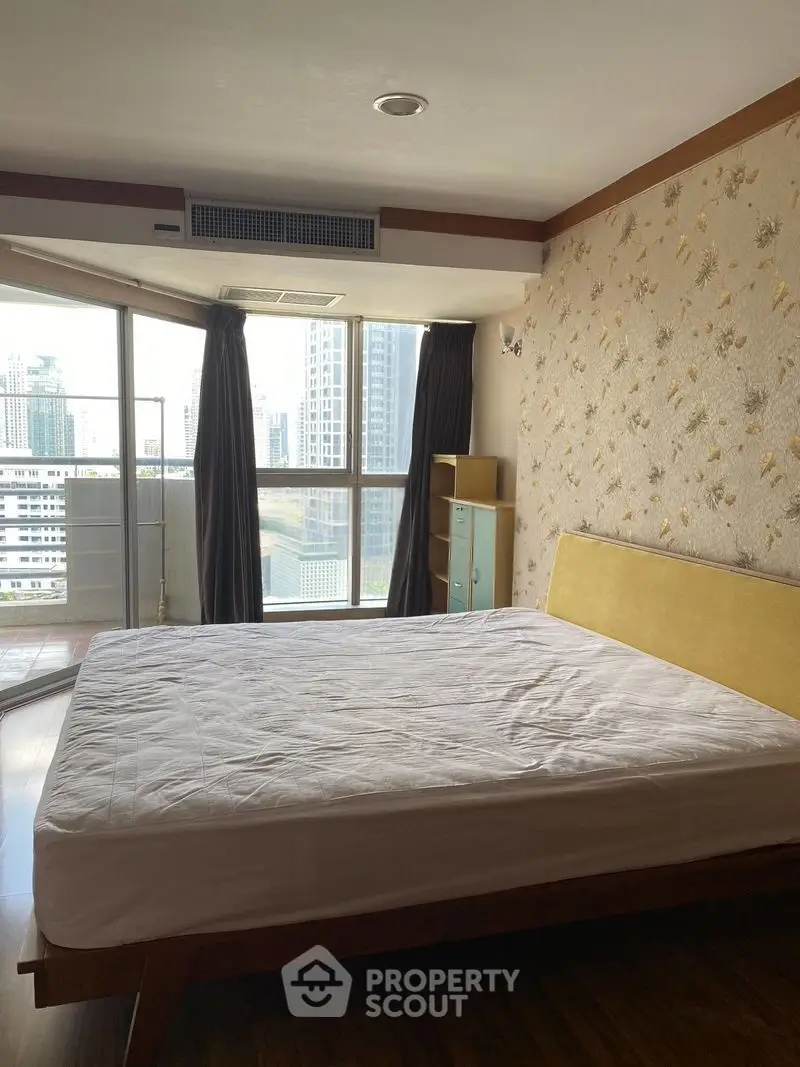 Spacious bedroom with large windows and city view, featuring modern decor and ample natural light.