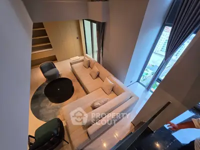 Modern living room with high ceiling and large windows offering city views
