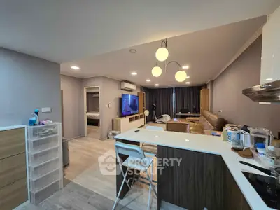 Modern open-layout living room with kitchen island and stylish lighting in a cozy apartment.