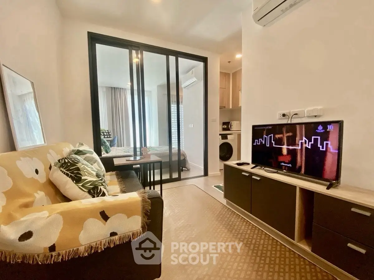 Modern living room with cozy sofa and TV, open layout to bedroom.