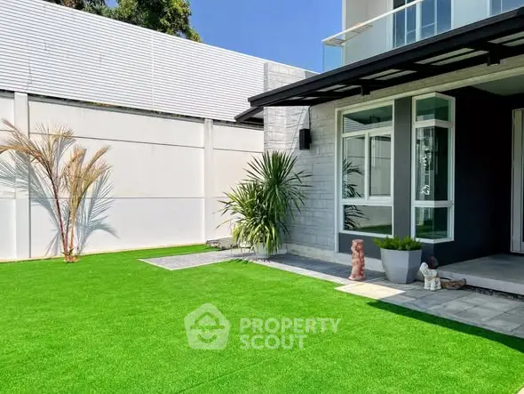 Modern home exterior with lush green lawn and sleek architectural design.