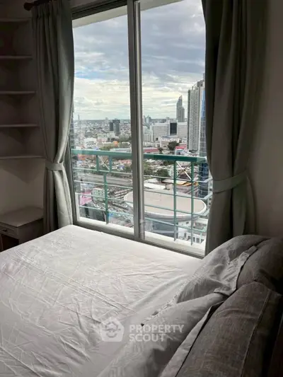 Cozy bedroom with stunning city view from high-rise window, perfect urban living.