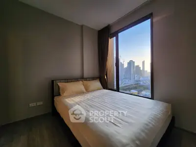 Modern bedroom with city view, featuring a large window and cozy bed.