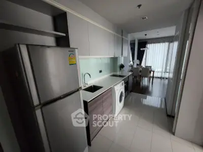 Modern kitchen with sleek appliances and open layout leading to dining area.