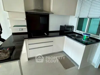 Modern kitchen with sleek black countertops and built-in appliances in a stylish apartment.