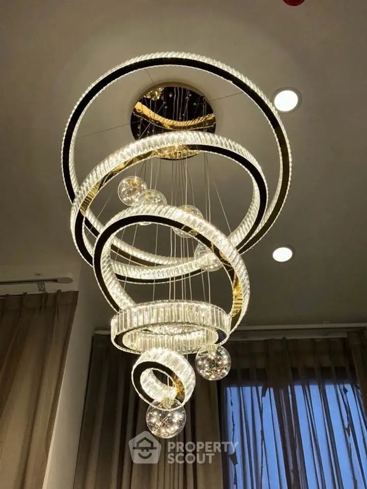 Elegant spiral chandelier in modern living room with floor-to-ceiling curtains.